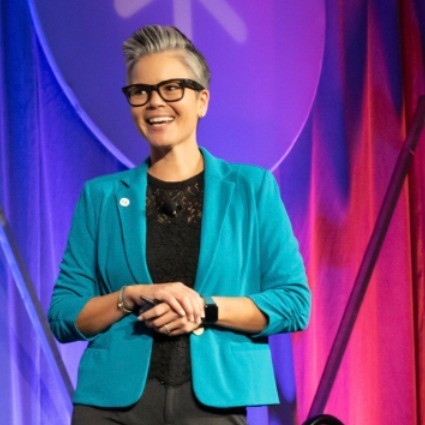 Amanda DevLugt holding up a quarter, presenting The Power of a Quarter keynote at SHIFT 2026.